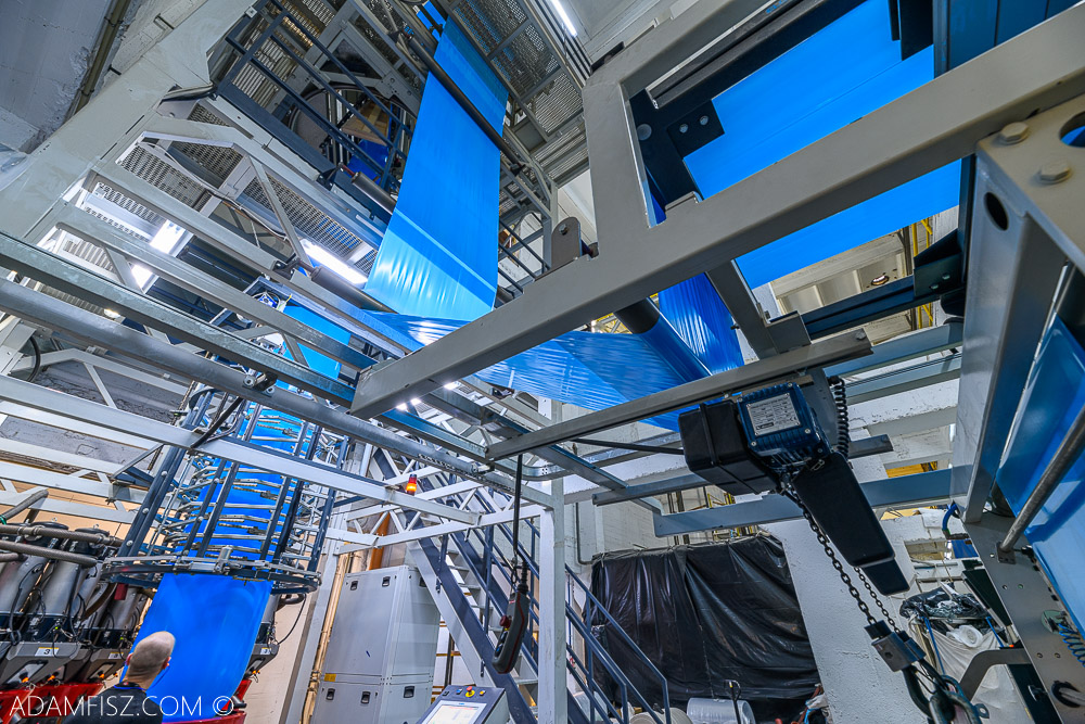 maszyny przemysłowe na hali produkujące niebieską folię