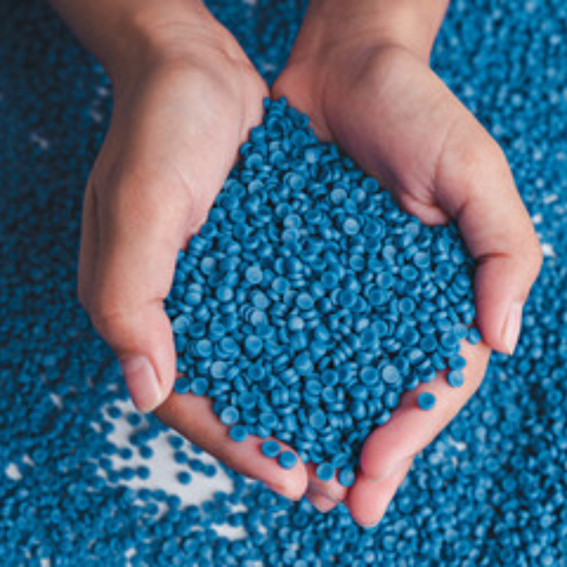 dłonie trzymają regranulat niebieski